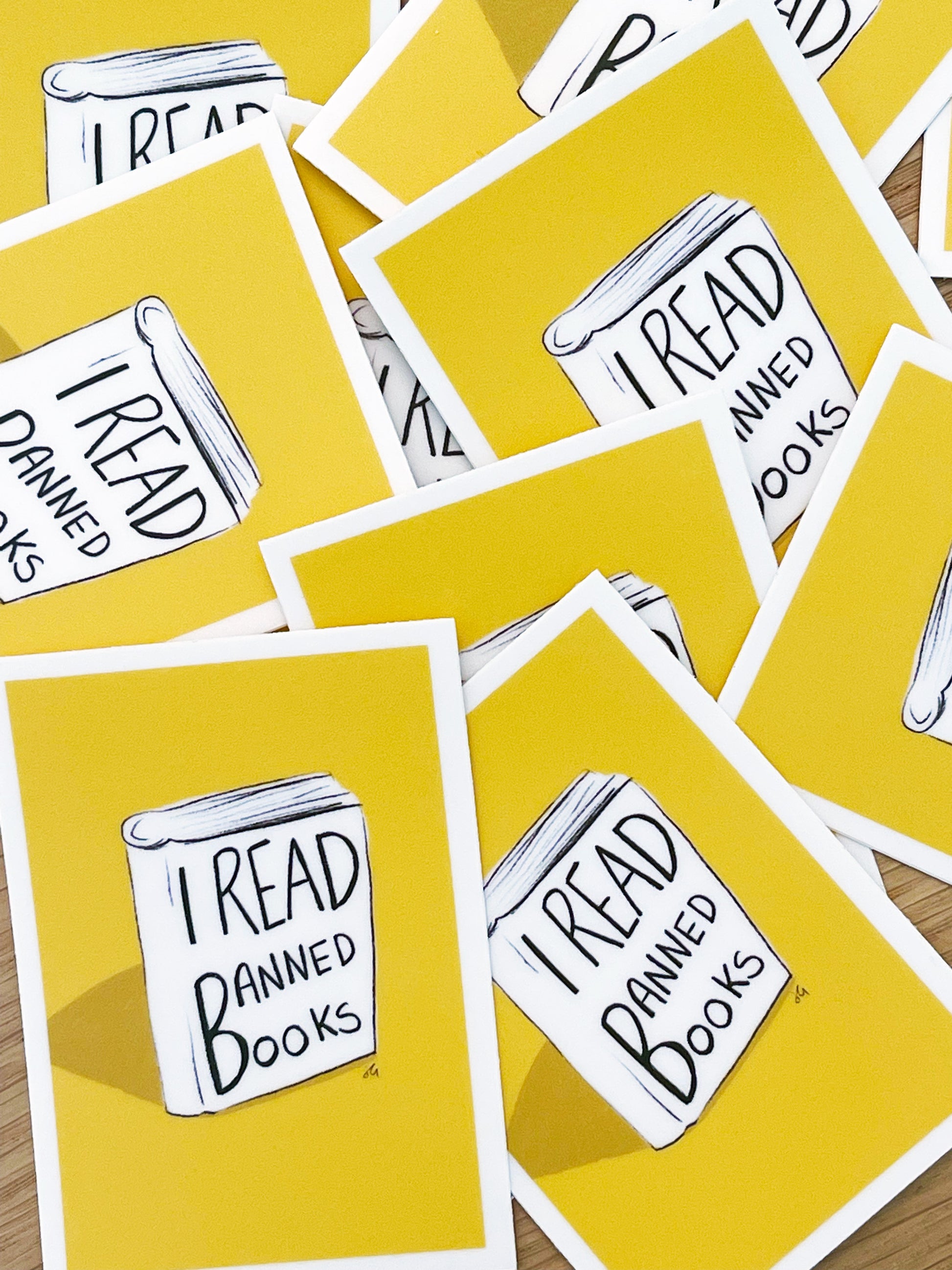 A pile stickers that has, I read banned books written on a illustrated book with a yellow background