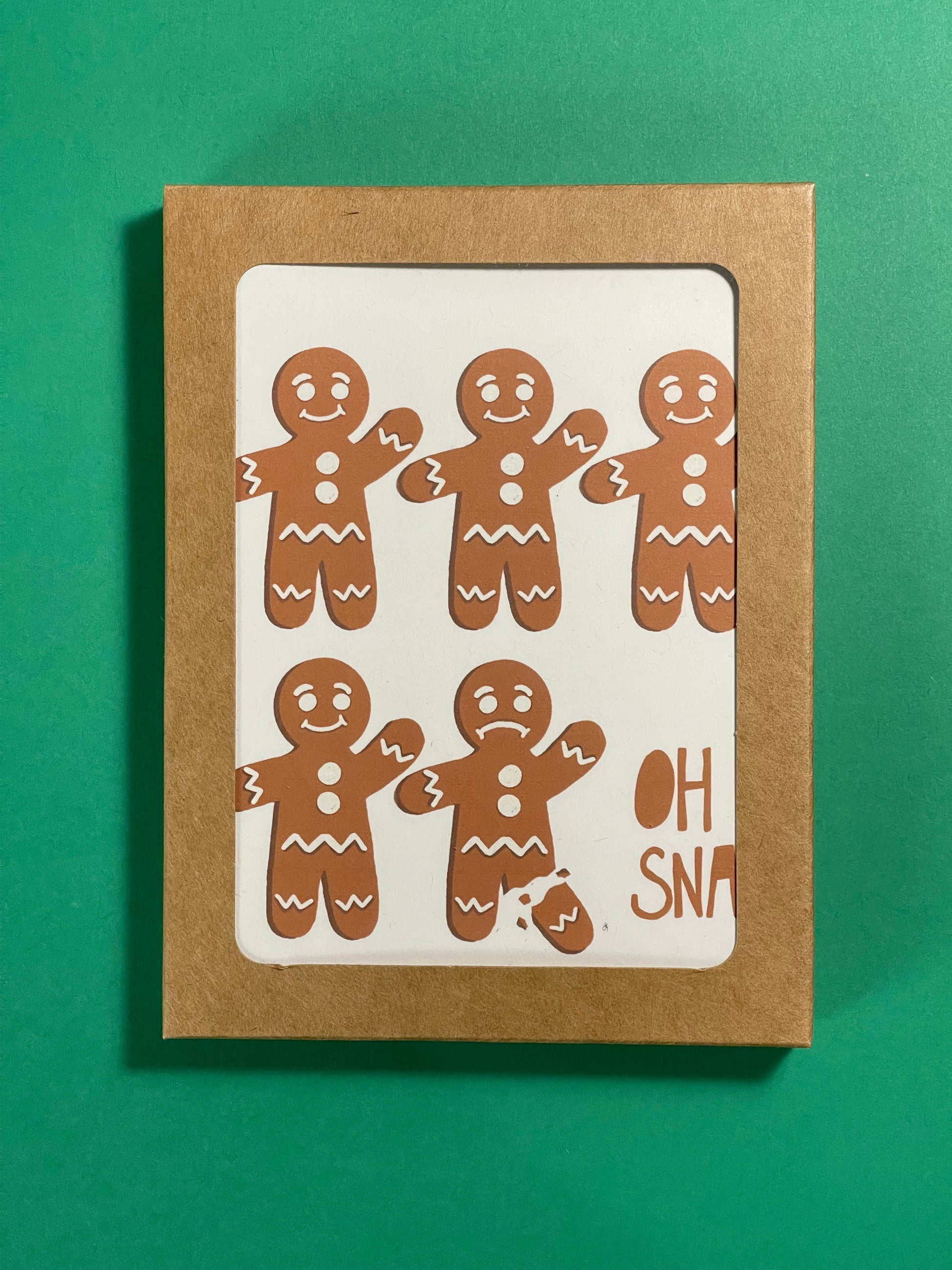 holiday greeting card with gingerbread that reads oh snap on the front and its the holidays inside. Showcased as a boxed card set