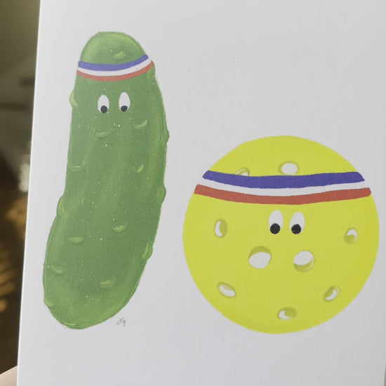 greeting card with a pickle and a ball with sweatbands around their hands. A pun on pickle ball